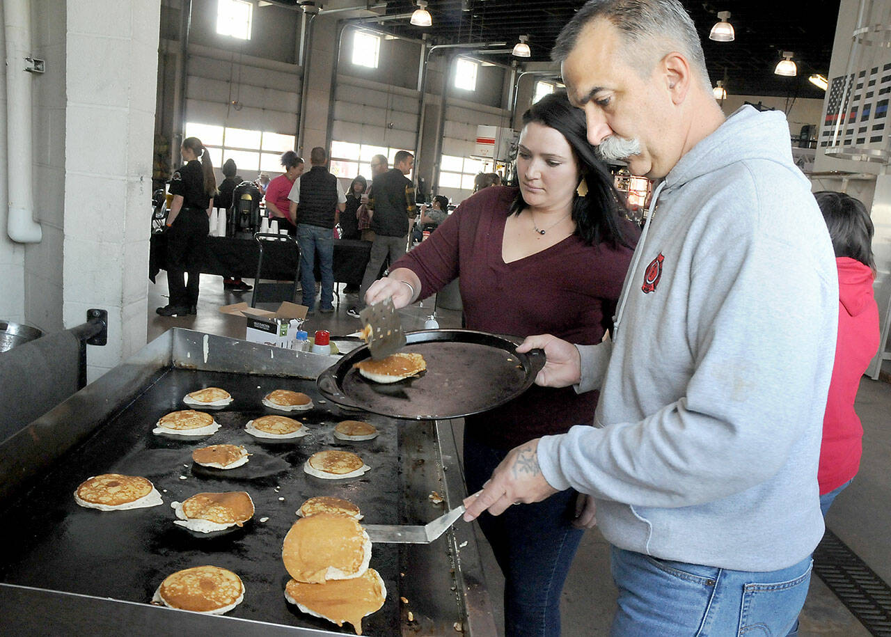 Port Angeles Fire Department paramedics Kristin Fox, left, and Brian Gerdes flip pancakes during the department’s annual pancake breakfast on Saturday at the fire hall. The event, which included a complete breakfast with beverage, was a fundraiser for fire department scholarships and community outreach. (Keith Thorpe/Peninsula Daily News)