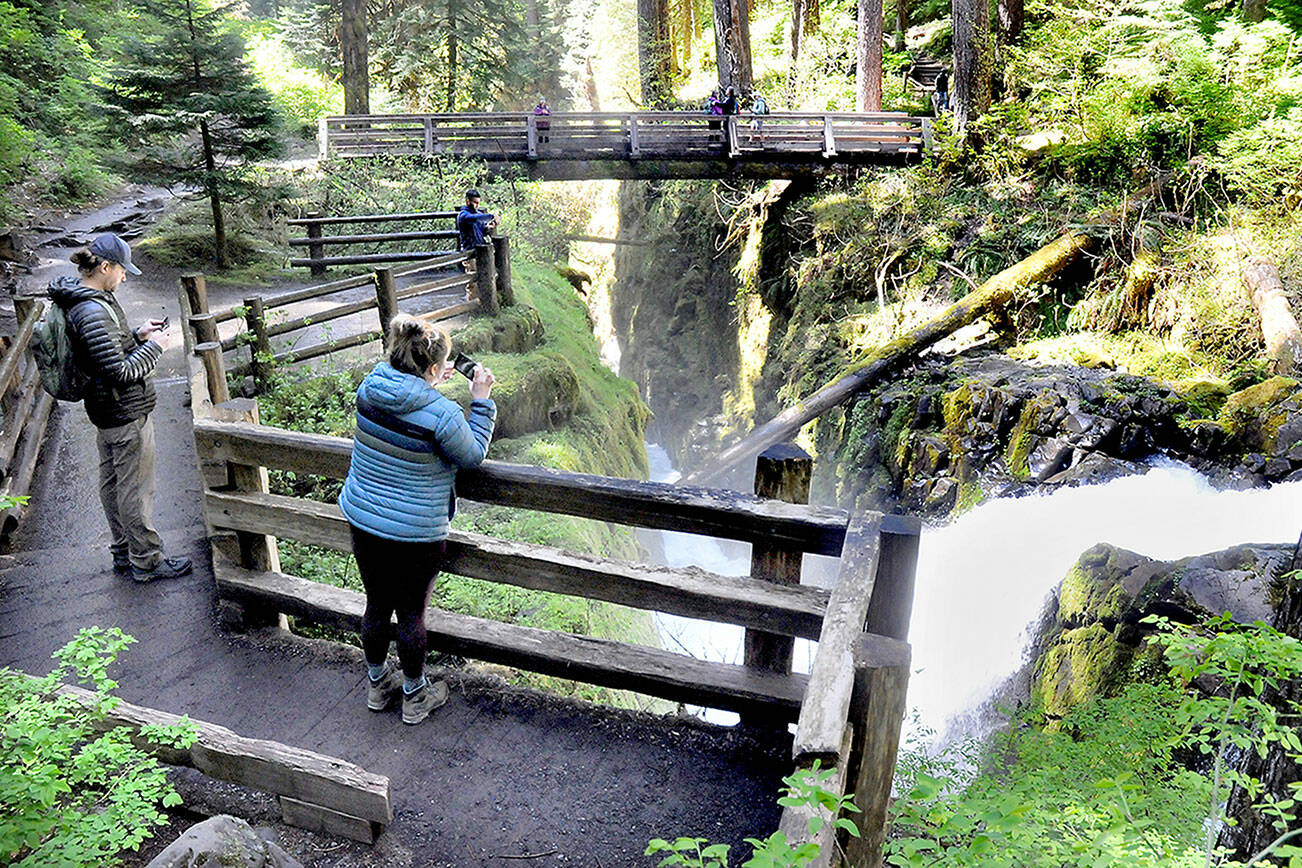 Alahan Sivam, left, and Kandice Ringer, both of Eugene, Ore., take cellphone photos of Sol Duc Falls in the Sol Duc River Valley of Olympic National Park on Monday. The pair visited the popular attraction while on a weeklong exploration of the park. (Keith Thorpe/Peninsula Daily News)