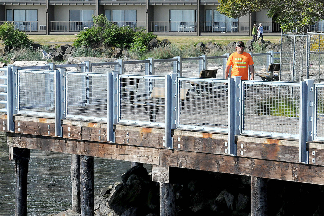Kevin Smith of Neely Construction Co. walks the perimeter next to newly installed railing panels on Thursday at Port Angeles City Pier. The first phase of pier railing replacement was completed on Thursday in a project that eliminates major portions of rusty steel edge barriers and the installation of 1,300 linear feet of galvanized steel pedestrian barriers. (Keith Thorpe/Peninsula Daily News)