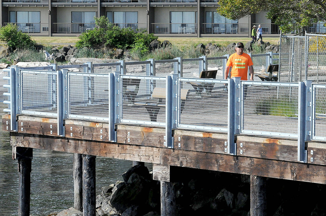 Kevin Smith of Neely Construction Co. walks the perimeter next to newly installed railing panels on Thursday at Port Angeles City Pier. The first phase of pier railing replacement was completed on Thursday in a project that eliminates major portions of rusty steel edge barriers and the installation of 1,300 linear feet of galvanized steel pedestrian barriers. (Keith Thorpe/Peninsula Daily News)