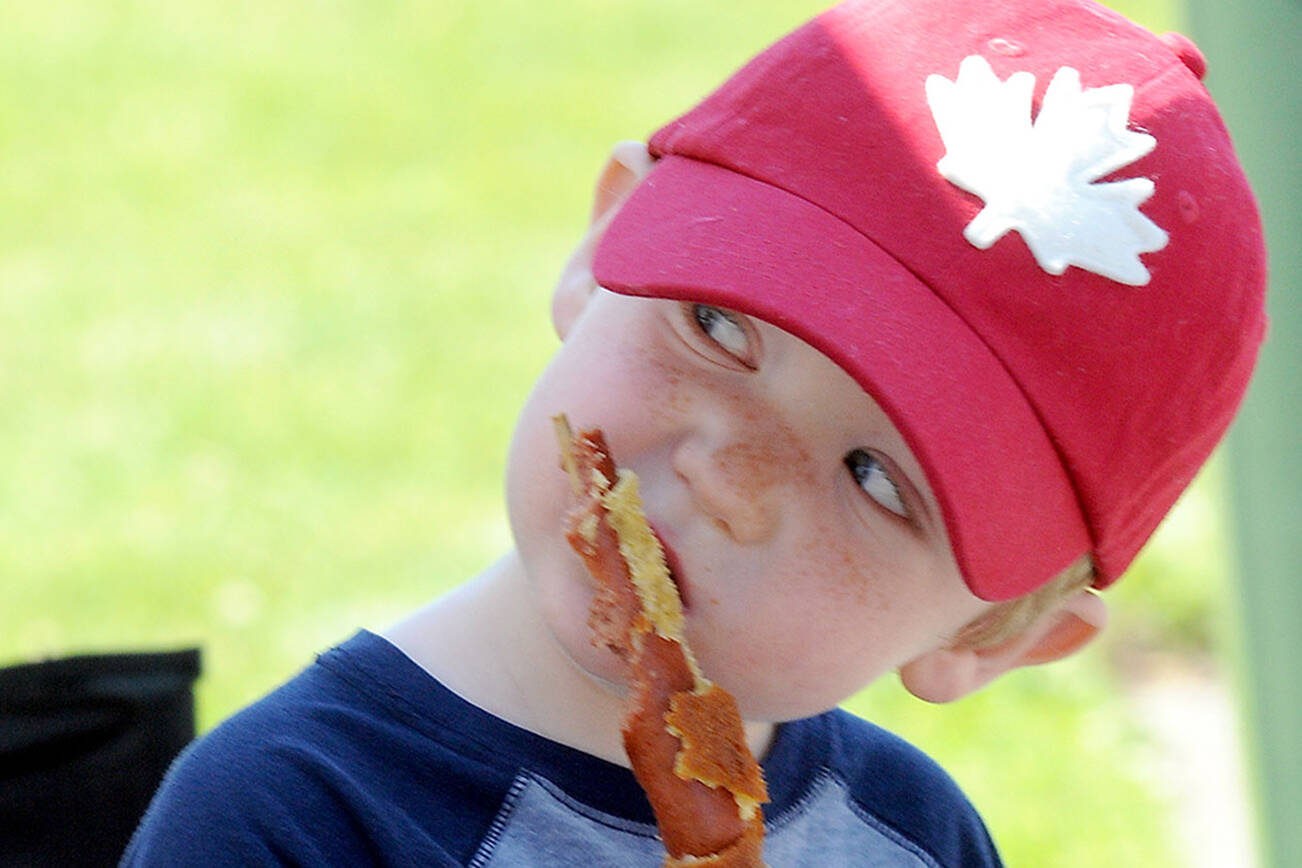 James Hershmiller, 3, of Port Angeles gnaws on a corn dog on Friday at the Juan de Fuca Festival street fair in Port Angeles. (KEITH THORPE/PENINSULA DAILY NEWS)