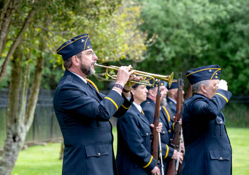 Rick Castellano of Whidbey Island stands beside the honor guard as he plays Taps during a Memorial Day Service at the military cemetery at Fort Worden State Park on Monday. (Steve Mullensky/for Peninsula Daily News)