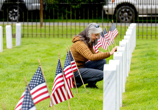 A woman is alone in her thoughts as she honors a veteran buried in the military cemetery at Fort Worden State Park on Monday. (Steve Mullensky/for Peninsula Daily News)