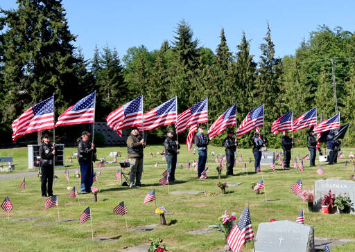 Attendees hold a row of American flags during Memorial Day ceremonies at Mt. Angeles Cemetery on Monday. (Dave Logan/for Peninsula Daily News)