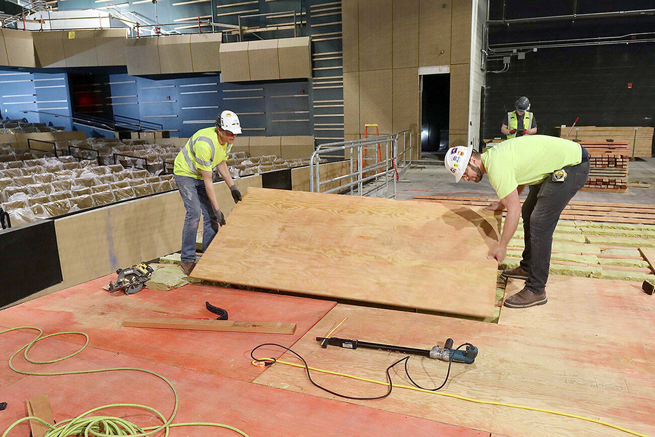 Matthew Sacks, left, and Levi Smith of Brandsen Co. from Portland, Ore., lay one of the layers on the new stage floor at the Field Arts and Events Hall in downtown Port Angeles. There will be a total of six layers of materials for the high-tech stage floor. The venue, which will seat 500, will begin to host performances when it opens at the end of July. (Dave Logan/for Peninsula Daily News)