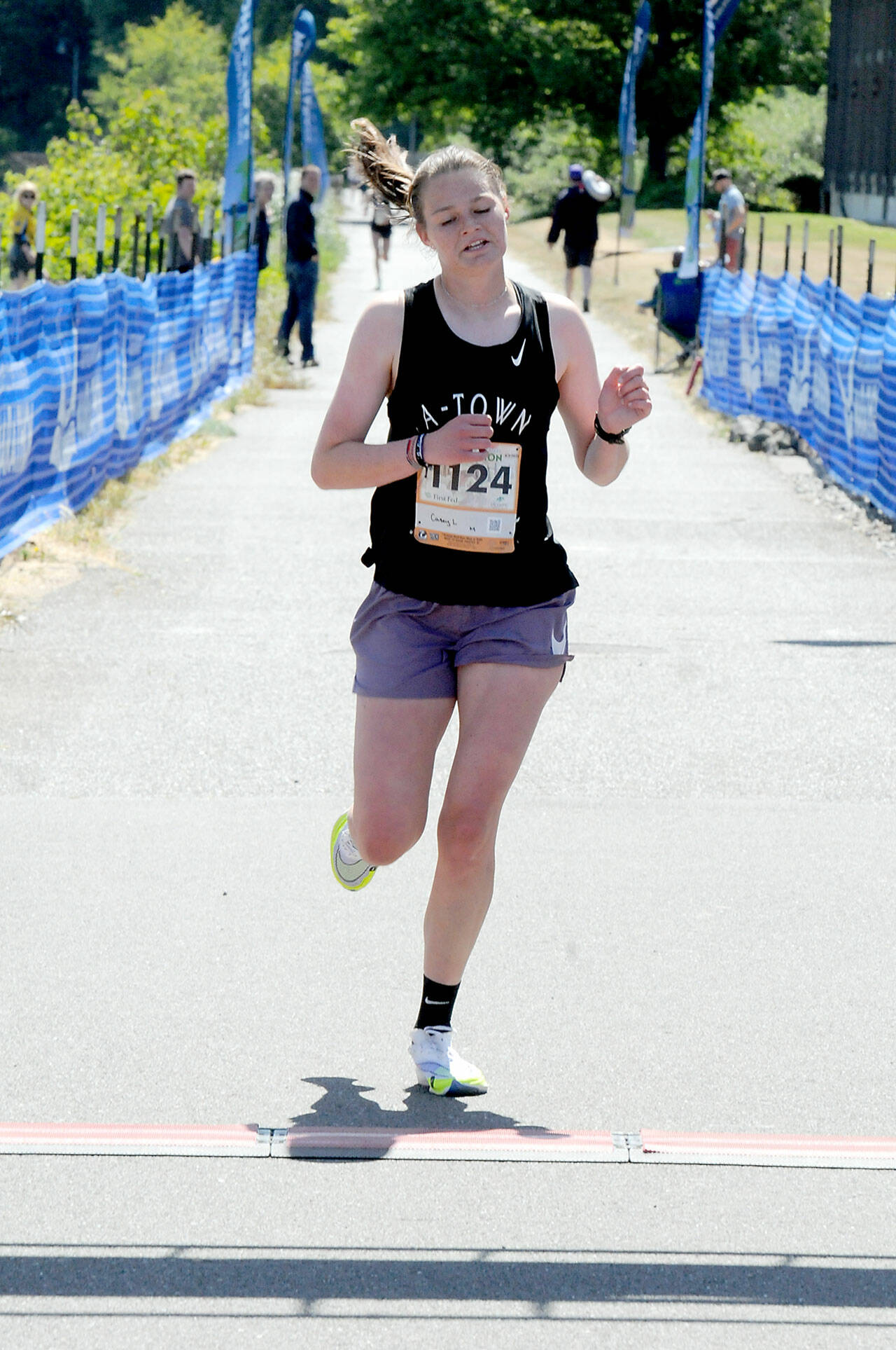 KEITH THORPE/PENINSULA DAILY NEWS Casey Lemrick of Anacortes, the top female winner of Saturday’s 5k race crosses the finish line at Port Angeles City Pier.