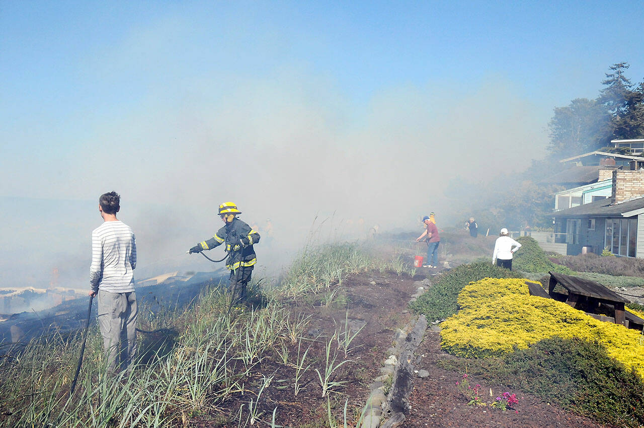 Firefighters and residents team up to beat down a beach fire that threatened numerous homes in the Four Seasons Ranch area east of Port Angeles on Saturday. (Keith Thorpe/Peninsula Daily News)