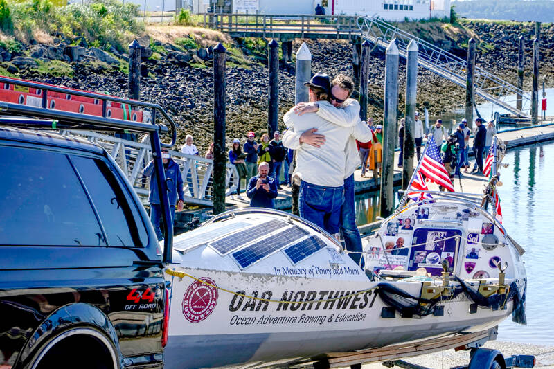 With emotions running high, the skipper of the boat, Jordan Hanssen, and crewman Greg Spooner share a hug as the boat is pulled up the ramp under the eyes of spectators lining the dock at the Port Townsend Boat Haven on Monday. (Steve Mullensky/for Peninsula Daily News)