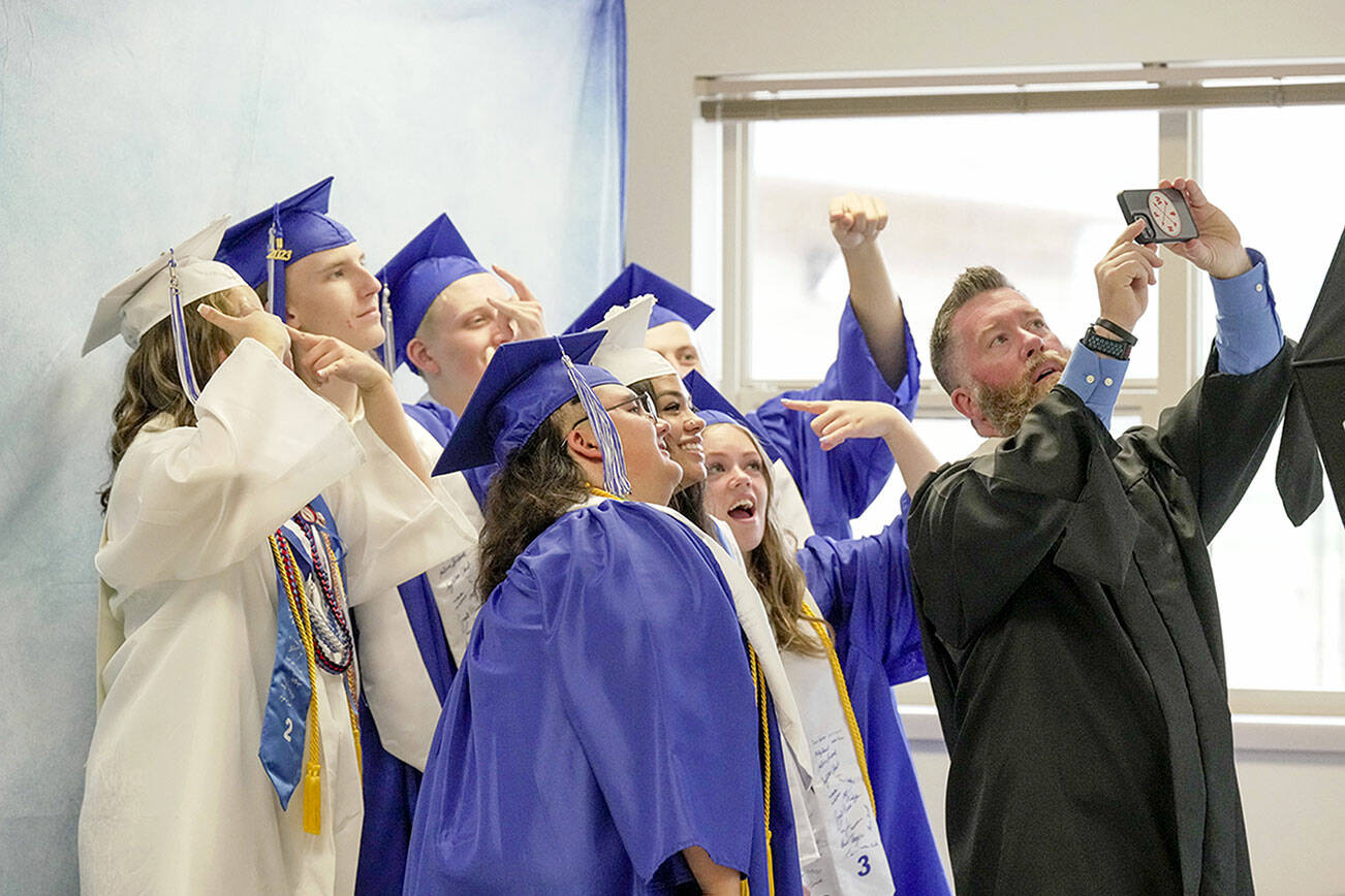 A group of graduating seniors take a selfie with teacher and head football coach Tony Haddenham while they wait for their graduation ceremony to begin on Saturday at Chimacum High School. (Steve Mullensky/for Peninsula Daily News)