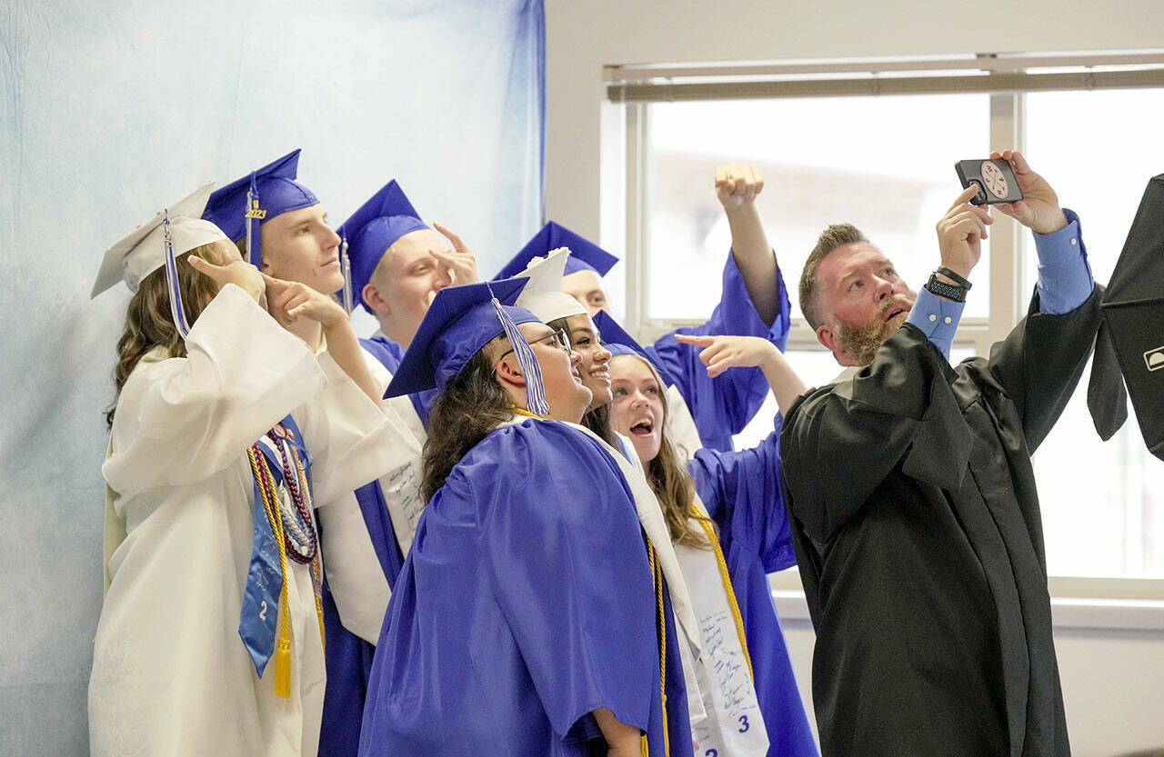 A group of graduating seniors take a selfie with teacher and head football coach Tony Haddenham while they wait for their graduation ceremony to begin on Saturday at Chimacum High School. (Steve Mullensky/for Peninsula Daily News)