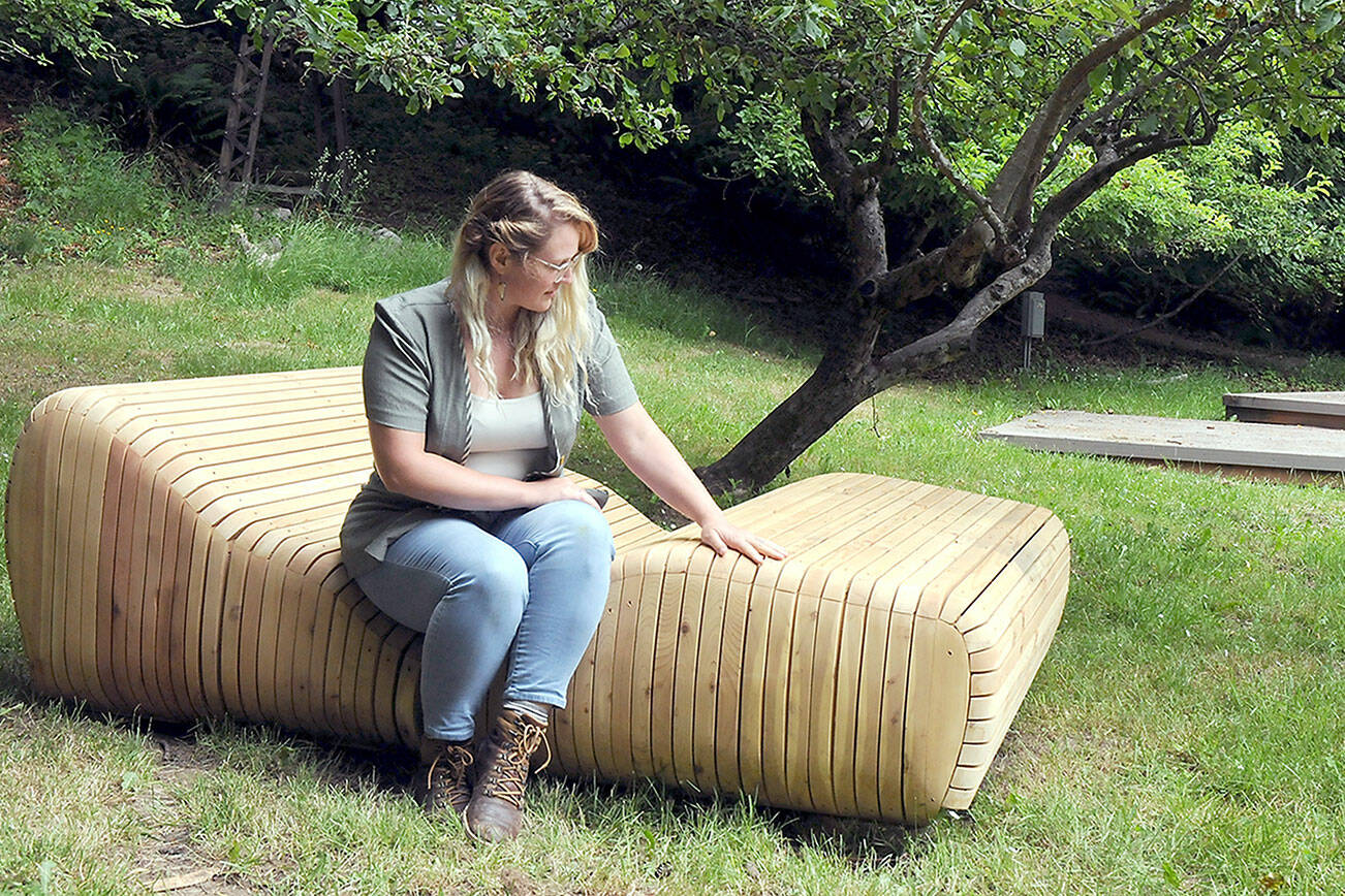 Rachel Storck, community engagement director for the Port Angeles Fine Arts Center, sits on the art installation “Sky Gazer” by Port Angeles artist Steve Belz, one of several new artworks in the Webster’s Woods Sculpture Park, the site of this weekend’s Summertide Solstice Arts Festival. (Keith Thorpe/Peninsula Daily News)