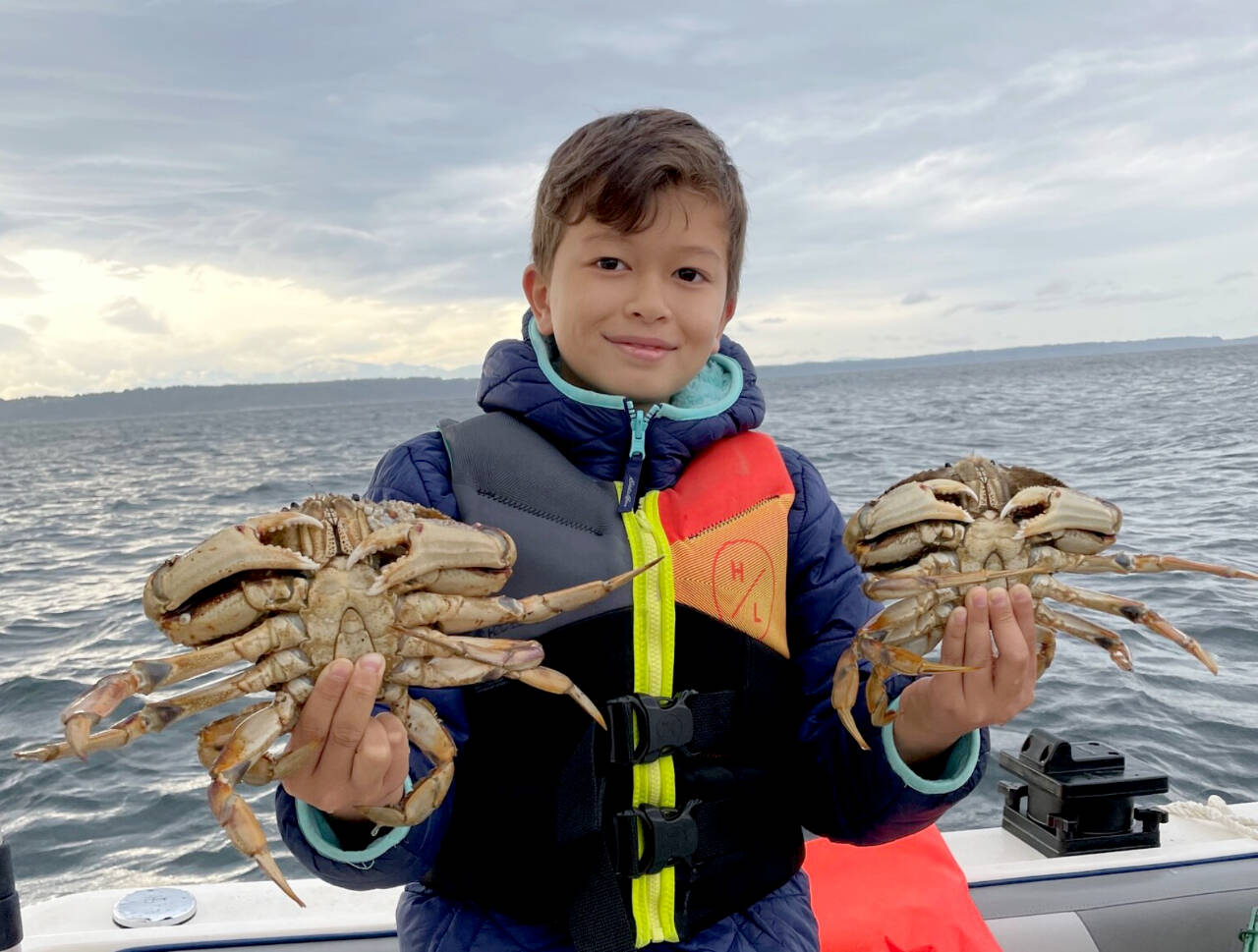 A young crabber holds his catch off the coast of Washington. (Claire Young/WDFW)