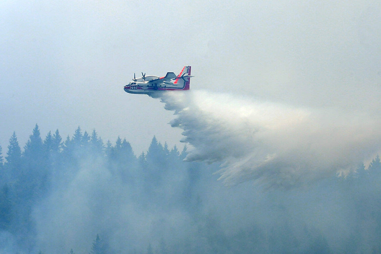 A “Super Scooper” aircraft makes a water dump on a flaming area of forest on Sunday in the Indian Creek Valley southwest of Port Angeles. (Keith Thorpe/Peninsula Daily News)