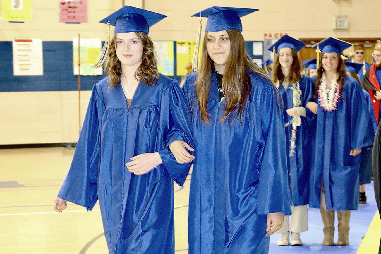 Leading the march of the 21 Crescent High School graduates are Harmony Henderson, left, and Rhylin Lium. Superintendent David Bingham presented the graduating class in front of a full house of family and friends in the high school gym. (Dave Logan/for Peninsula Daily News)