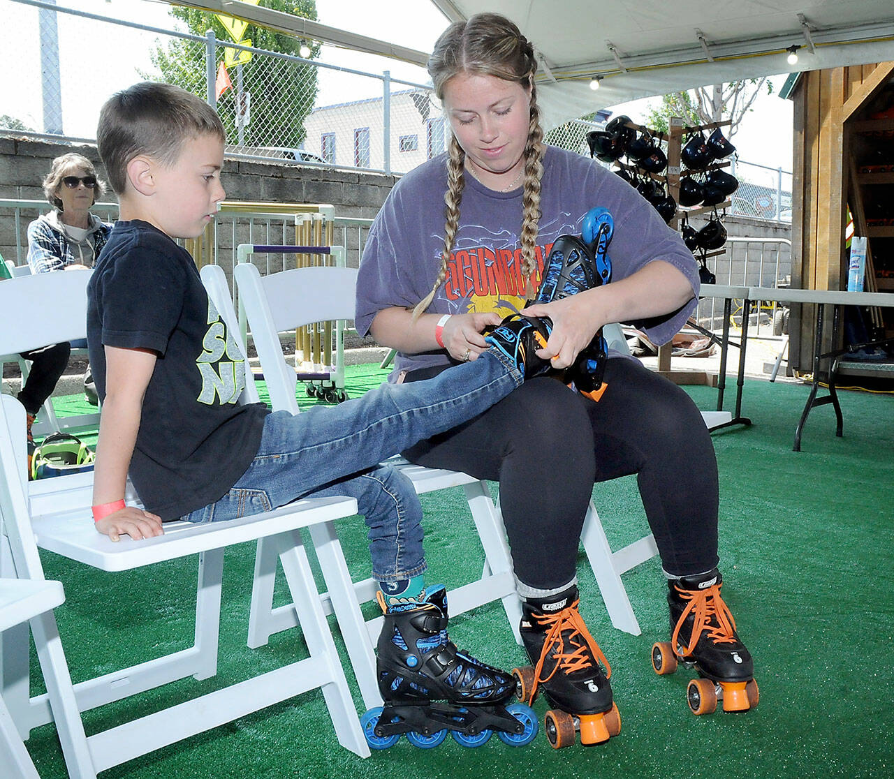 Devyn Roblan of Port Angeles makes adjustments to a rollerblade worn by her son, Miles Roblan, 7, on Friday’s opening day of skating at the seasonal Olympic Skate Villege in downtown Port Angeles. (KEITH THORPE/PENINSULA DAILY NEWS)