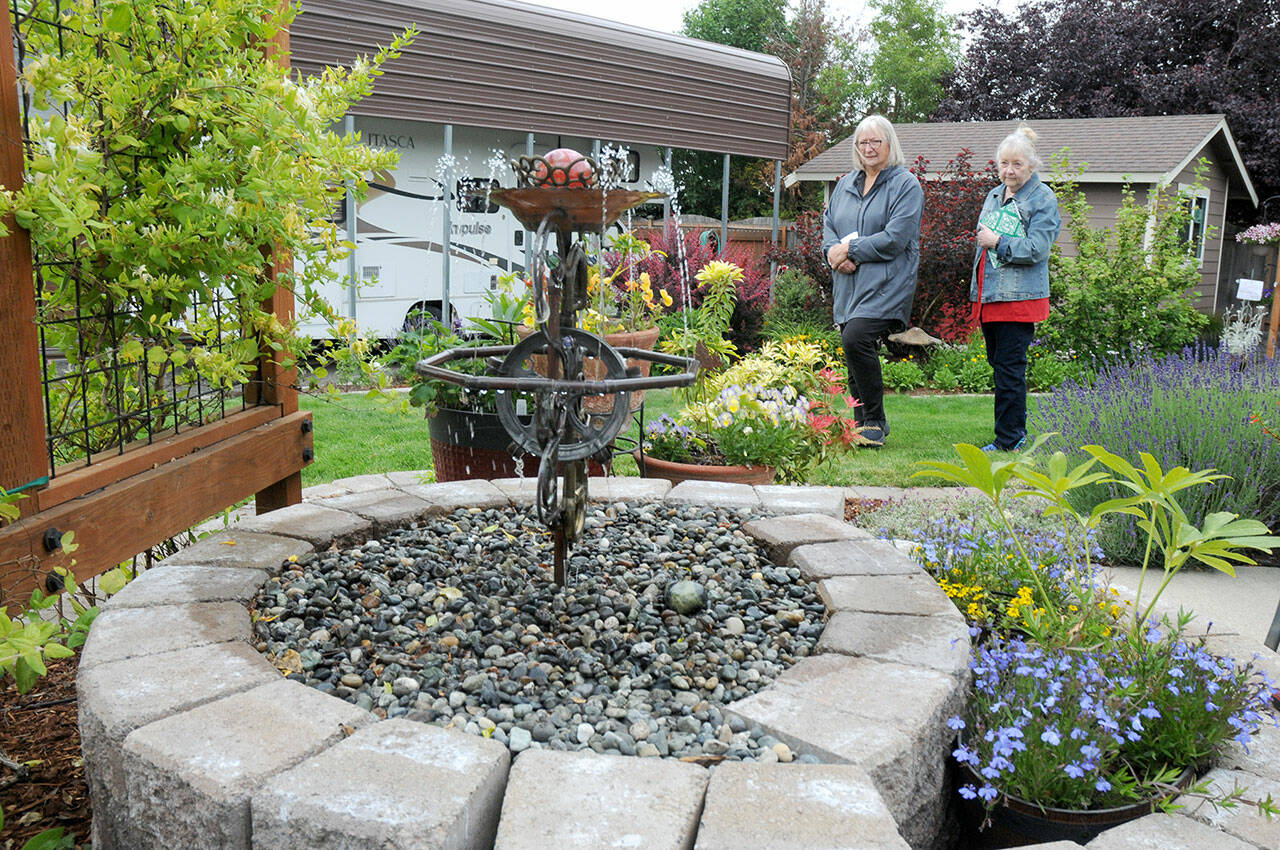 Dorothy Hoffman, left, and Anne Steurer, both of Port Townsend, examine a water feature in the backyard garden of Niki Kobes and Tom Riette in Carlsborg, one of five featured gardens during Saturday’s 28th annual Petals & Pathways home garden tour. The event was hosted by the Master Gardener Foundation of Clallam County. (Keith Thorpe/Peninsula Daily News)