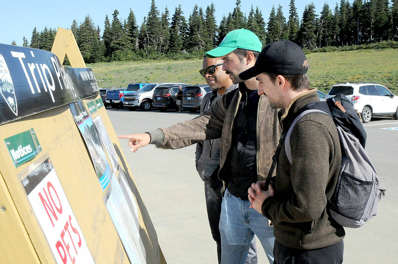 Olympic National Park visitors, from left, Nelson Nunez, Mateo Sancho and Albert Martinez, all from New York City, look at an information board at Hurricane Ridge after the area was reopened to the public on Tuesday. (Keith Thorpe/Peninsula Daily News)