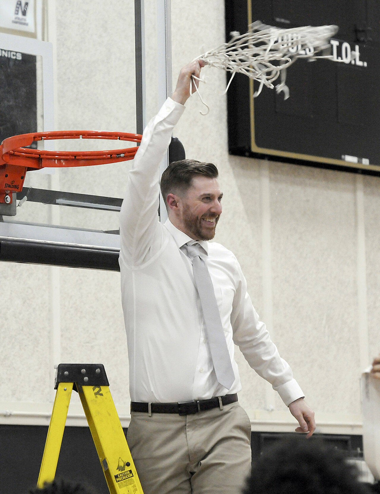 Donald Rollman, head coach of the Peninsula Pirates men’s team, waves a cut net in triumph after Peninsula clinched the NWAC North Region championship in February. (Keith Thorpe/Peninsula Daily News)