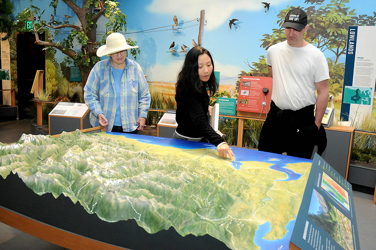 KEITH THORPE/PENINSULA DAILY NEWS
Dungeness River Nature Center visitors, from left, Chris McDonald of Port Angeles, Tram Pham of Huntington Beach, Calif., and Paul McDonald of Redmond examine a relief map display of the Dungeness River Watershed on Wednesday in Sequim. The center at Railroad Bridge Park offers a variety of displays and exhibits showcasing the nature and geography of the Dungeness River Valley.
