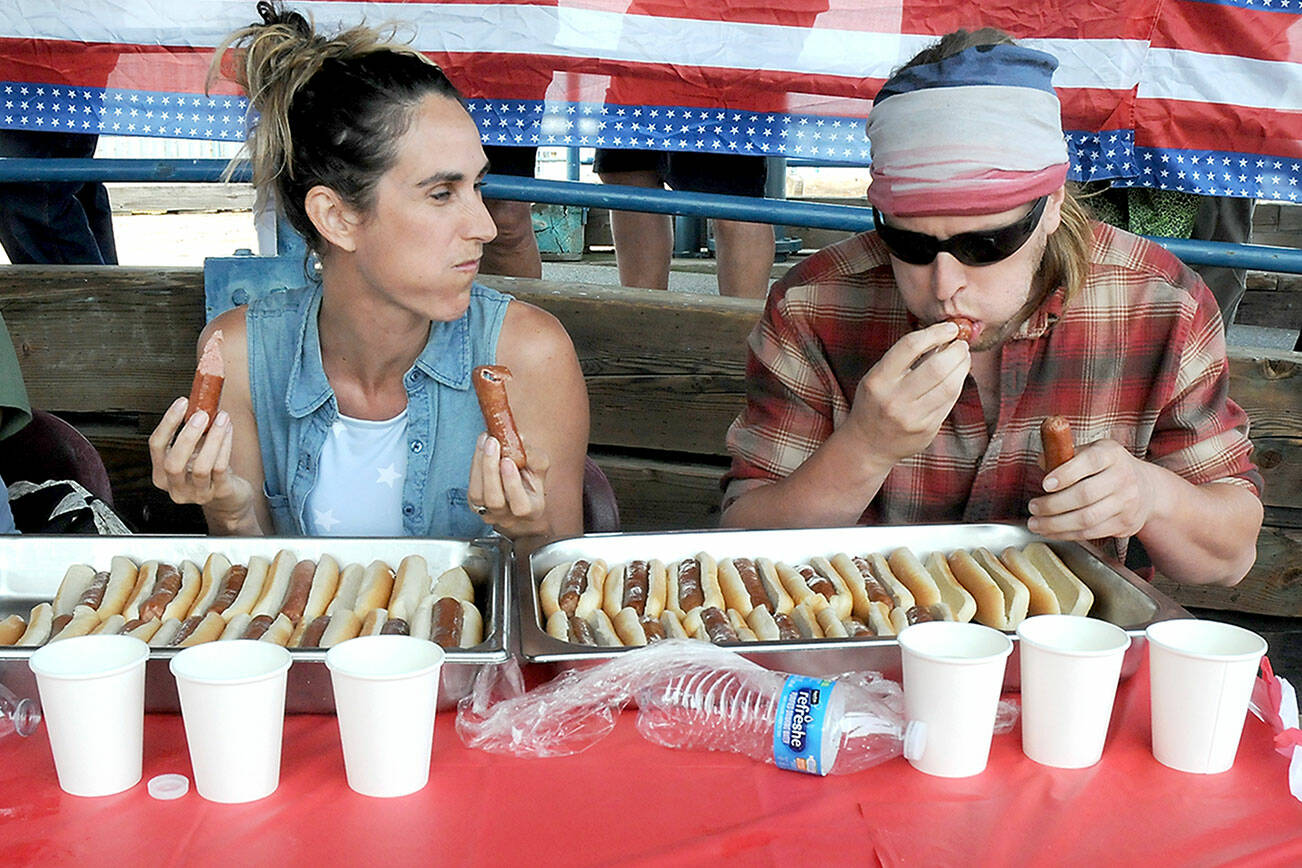 Contestant Jennifer Wilson, left, looks over as her fiancé, Jess Pinnell, downs hot dogs during Tuesday’s Independence Day eating contest at Port Angeles City Pier. Pinnell, of Port Angeles, went on to win the event, downing 10 dogs in 10 minutes. (Keith Thorpe/Peninsula Daily News)