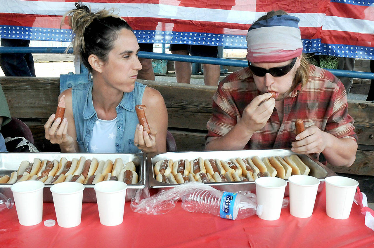 Contestant Jennifer Wilson, left, looks over as her fiancé, Jess Pinnell, downs hot dogs during Tuesday’s Independence Day eating contest at Port Angeles City Pier. Pinnell, of Port Angeles, went on to win the event, downing 10 dogs in 10 minutes. (Keith Thorpe/Peninsula Daily News)