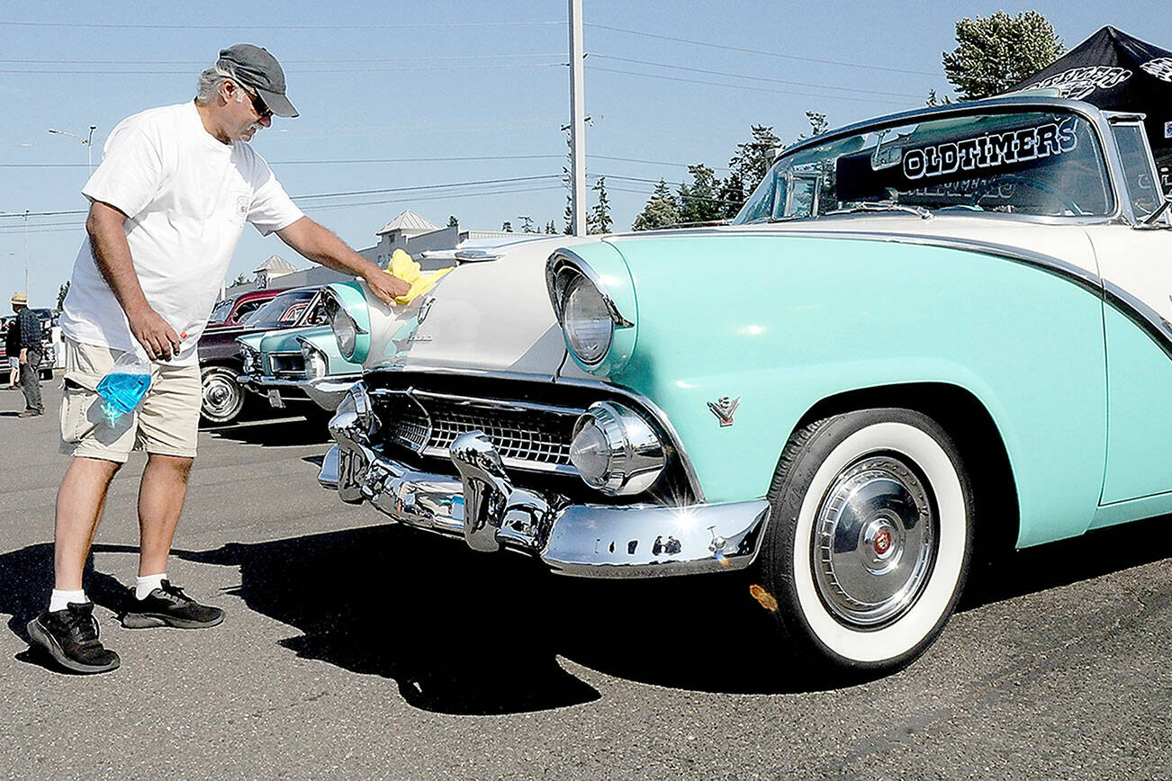 Mike Nikolaus of Chico polishes up his 1955 Ford Fairlane Sunliner during Friday’s 26th annual Ruddell Cruise In car show at Ruddell Auto Mall in Port Angeles. The event drew hundreds of people to view dozens of antique and vintage automobiles for an evening of food, music and automotive nostalgia. (Keith Thorpe/Peninsula Daily News)