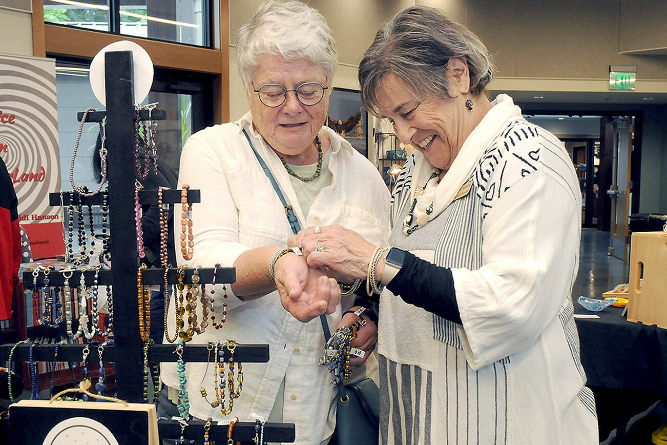 Carol Pearson of Sequim-based Lizzie Betz Jewelry assists Maureen Kennedy of Port Angeles with a bracelet during Saturday’s Rain Shadow Artisans Fair at the Dungeness River Nature Center in Sequim. The event brought together more than a dozen local crafters with the opportunity to market their wares. (Keith Thorpe/Peninsula Daily News)