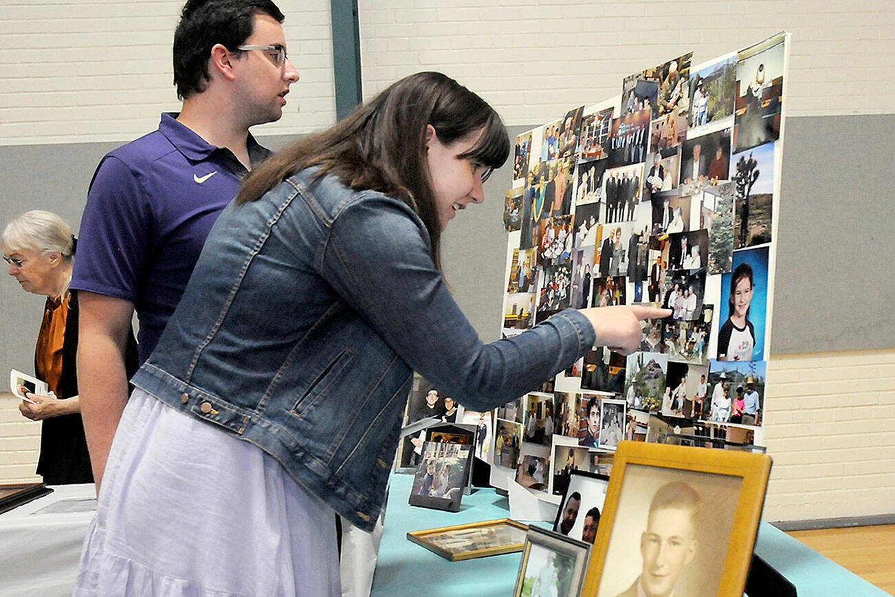 Ian Campbell of Bellevue, left, and Colette Campbell of Orlando, Fla., grandchildren of the late Port Angeles City Council member Orville Campbell, examine a table collection of family photos prior to a memorial service for the elder Campbell on Tuesday at Vern Burton Community Center in Port Angeles. (Keith Thorpe/Peninsula Daily News)