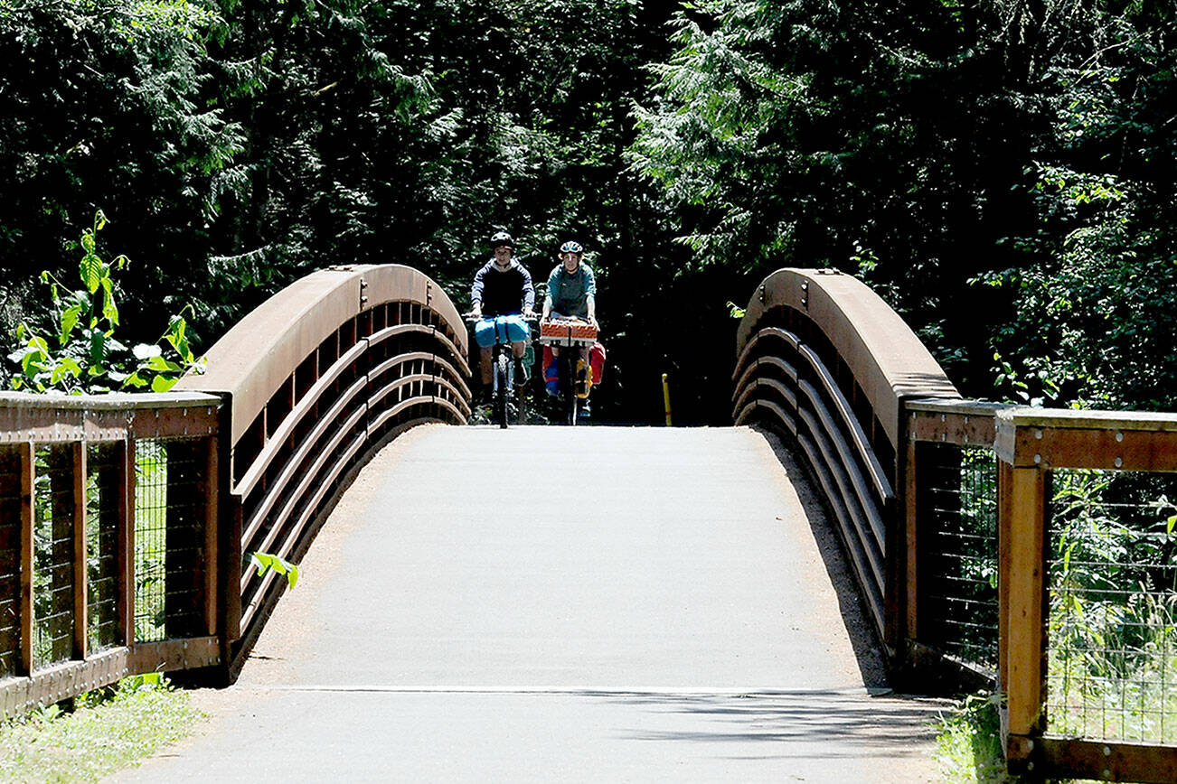 KEITH THORPE/PENINSULA DAILY NEWS
Tom Rooney of Seattle, left, and Marie Cazanave of Montreal, Quebec ride their bicycles over a 201-foot long footbridge spanning a small creek on Thursday at Sequim Bay State Park east of Sequim. The pair were on a bicycle camping excursion along the Olympic Discovery Trail.