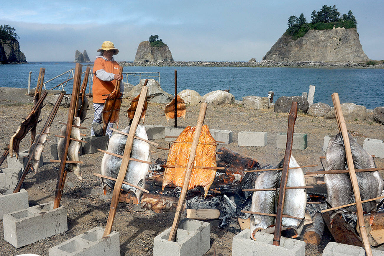 Quileute Tribal member Dana Williams prepares baked salmon in the old traditional way on Saturday while the Quillayute River flows to the sea. This tradition is included in the Quileute Days celebration held each year at LaPush. (Lonnie Archibald/for Peninsula Daily News)