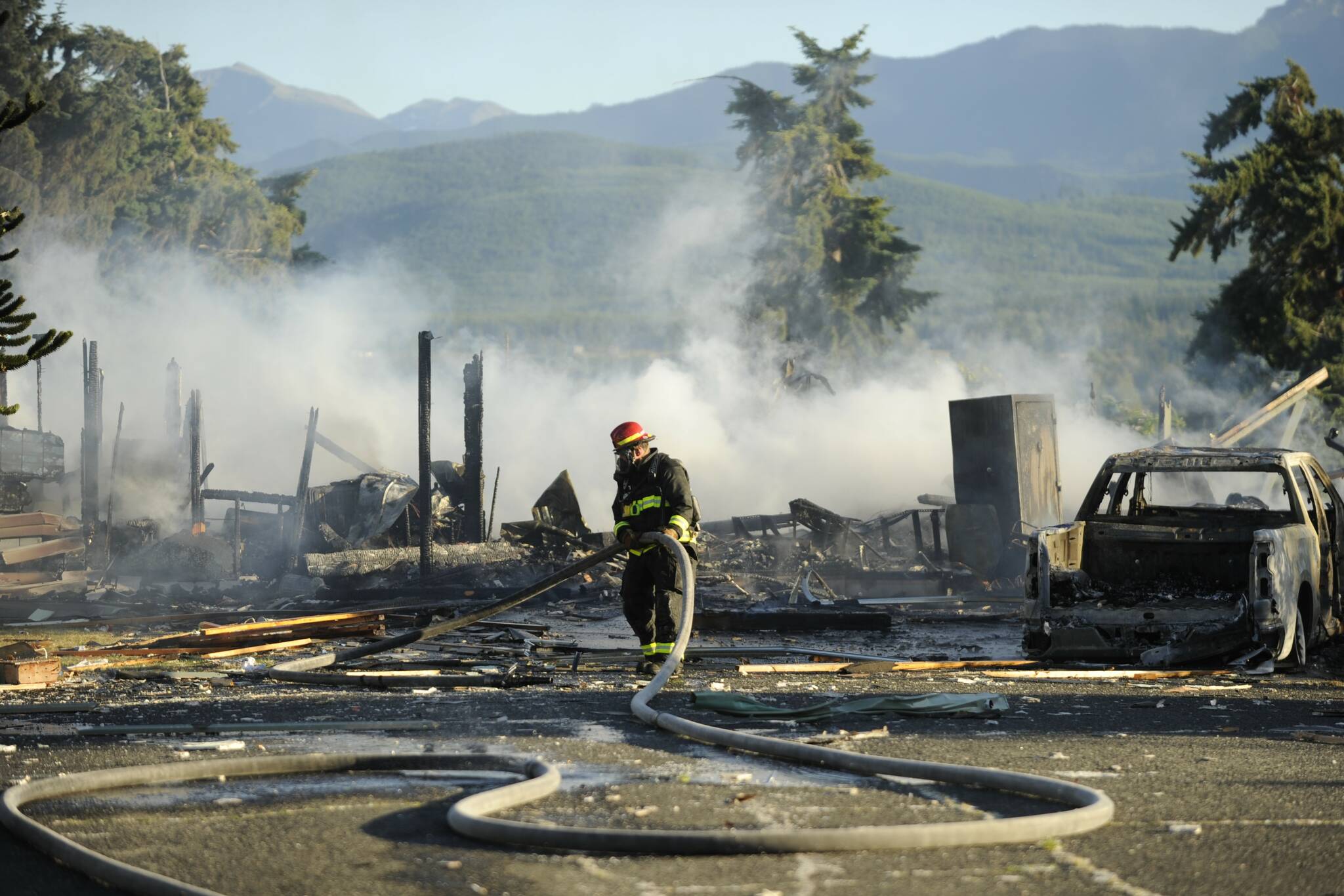 Firefighters with Clallam County Fire District 3 extinguish a fire after a home exploded on the 100 block of June Place on Tuesday evening. (Michael Dashiell/Olympic Peninsula News Group)