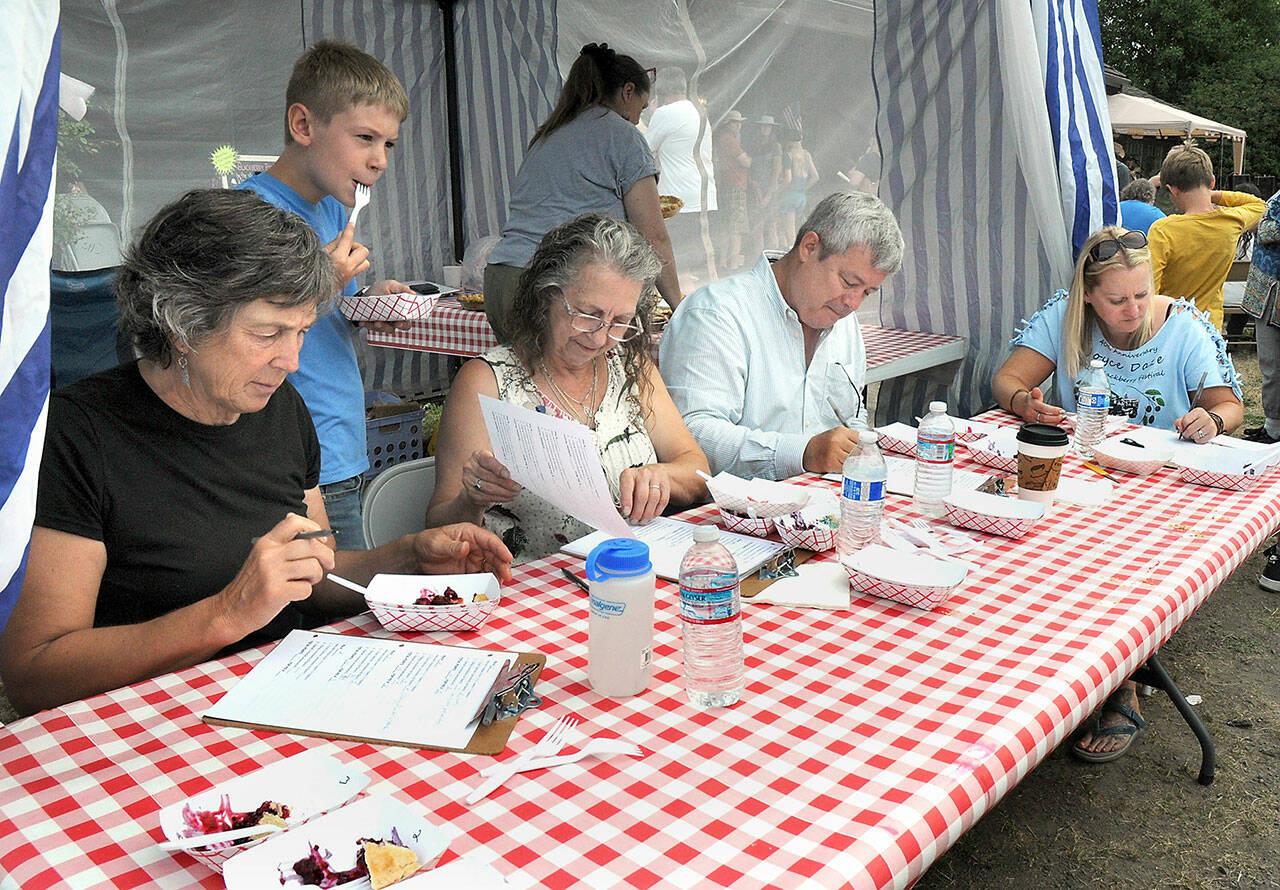 Blackberry pie contest judges, from left, Deb Moriarity, Roxanne Olsen, John Hauck and Holly Rose, along with unofficial judge William Erickson, 9, Olsen’s grandson, sample pies and take notes on Saturday. (Keith Thorpe/Peninsula Daily News)
