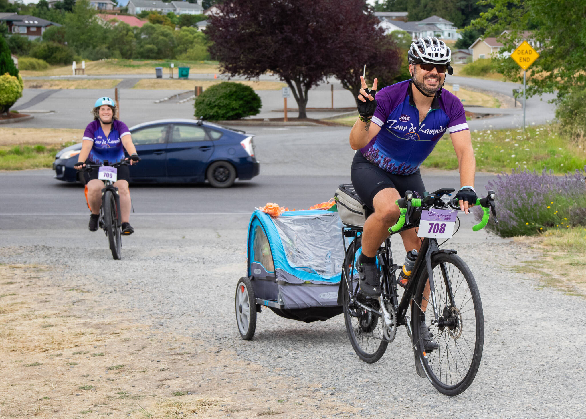 Stephen Fisher, from the Kenmore area, tows 2-year-old Juniper and pugs Jackie and JoJo, with wife Catherine Creason following. They participated in the couple’s sixth Tour de Lavender this weekend. Creason said they were married during the event five years ago. (Emily Matthiessen/Olympic Peninsula News Group)