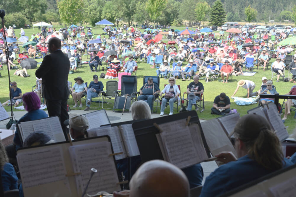 Photo by Richard Greenway, Sequim City Band/ A summer crowd settles in as Sequim City Band members and director Tyler Benedict prepare to play during the opening announcement of the Fourth of July concert.