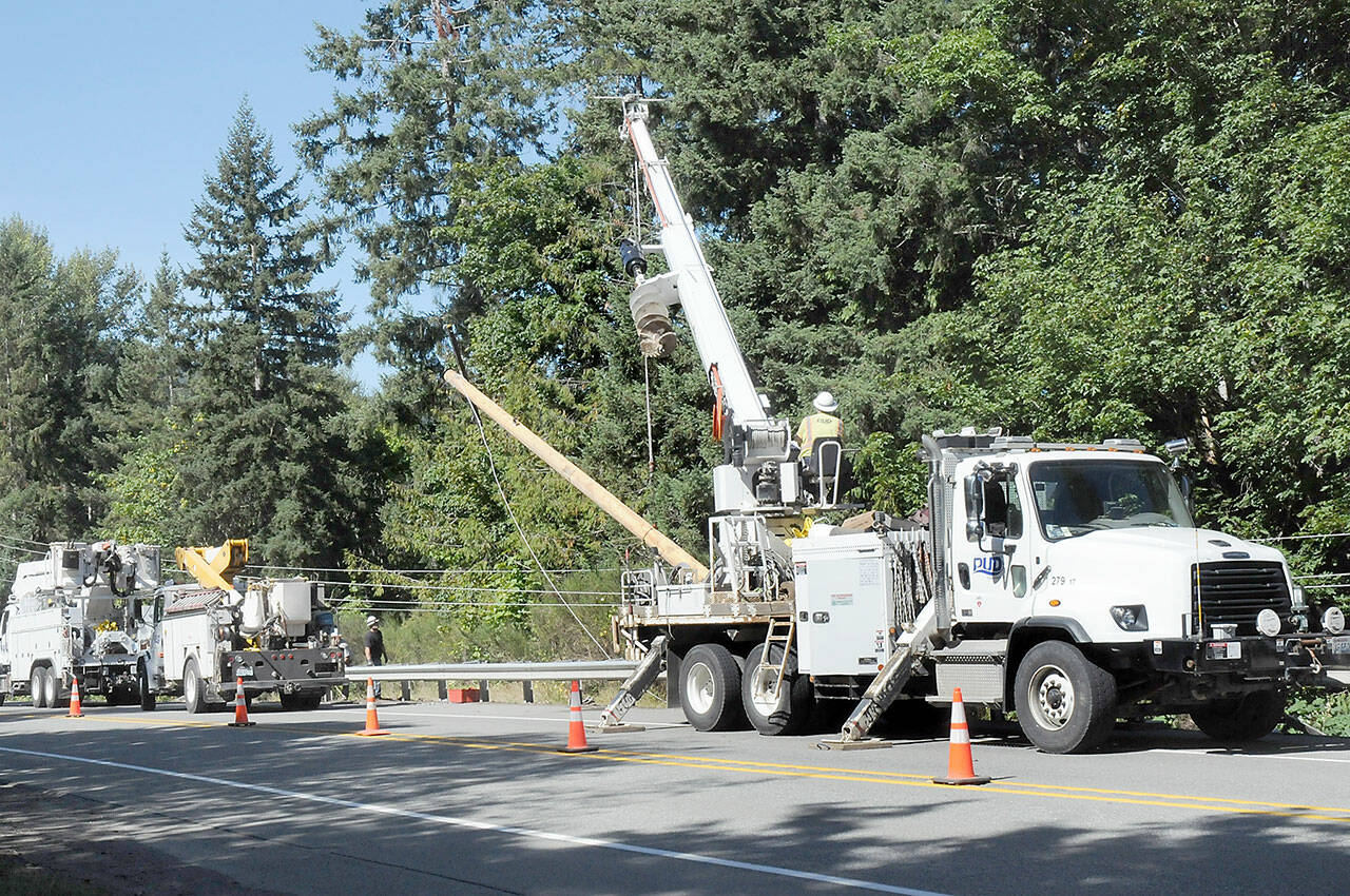 Clallam County Public Utility District crews erect a broken power pole along U.S. Highway 101 at Wildcat Road west of Port Angeles on Wednesday. (KEITH THORPE/PENINSULA DAILY NEWS)