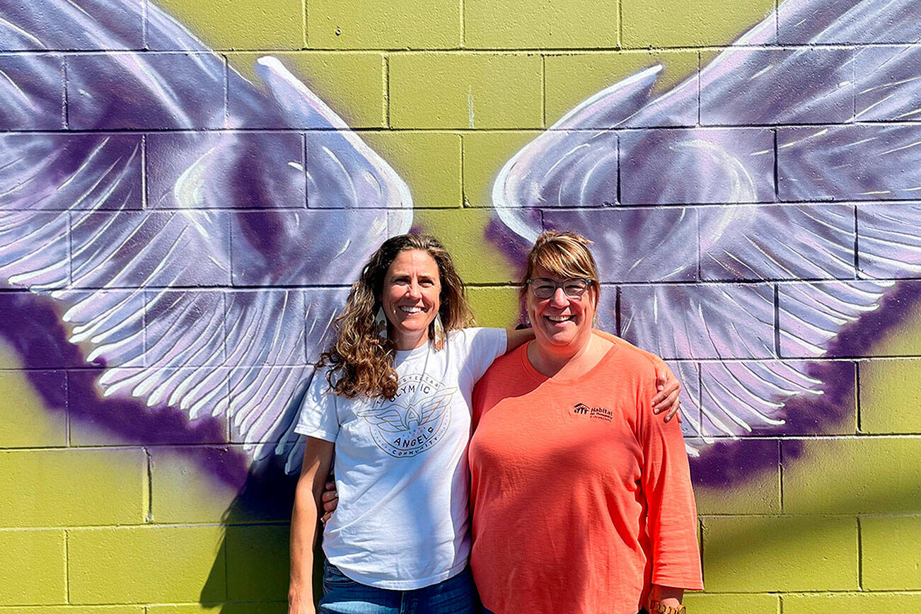 A mural by Craig Robinson in downtown Sequim represents a new partnership between Olympic Angels and Habitat for Humanity of Clallam County. Executive director Morgan Hanna with Olympic Angels, left, said they seek volunteers and mentors to help foster families. Colleen Robinson, chief executive officer for Habitat, said people are welcome to take photos on the wall of Habitat’s Boutique Store and they’ll place a sandwich board sign with information outside, and provide pamphlets about Olympic Angels during business hours. (Matthew Nash/Olympic Peninsula News Group)