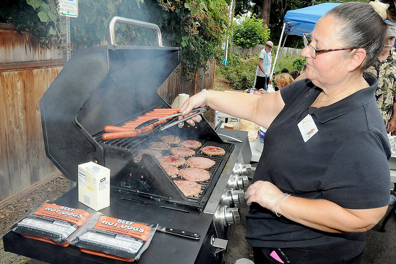 KEITH THORPE/PENINSULA DAILY NEWS
Diana Bossell, dietary manager with Peninsula Behavioral Health, grills hot dogs and hamburgers during a barbecue picnic and resource fair in honor of Overdose Awareness Day, observed on Thursday at Peninsula Behavioral Health’s Horizon Center in Port Angeles. The event, co-hosted by the North Olympic Healthcare Network, was designed to raise awareness of substance abuse and the effects of overdoses on victims and their families. Overdose Awareness Day included a rally at the Clallam County Courthouse and a remembrance march to Port Angeles City Pier.
