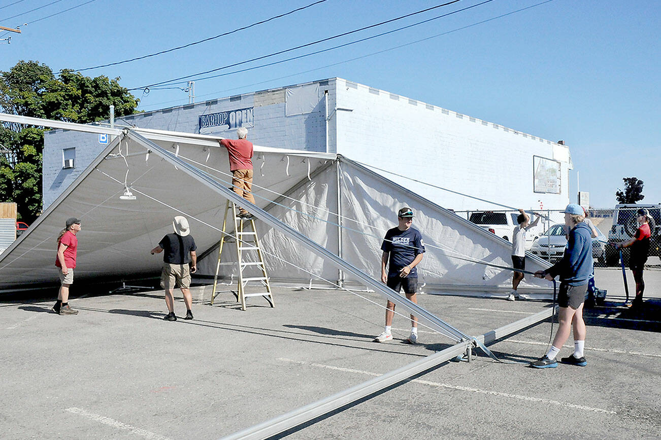 KEITH THORPE/PENINSULA DAILY NEWS
A work crew erects a tent in a city parking lot in the 100 block of West Front Street in downtown Port Angeles on Friday in preparation for Sunday's First Federal centennial celebration.