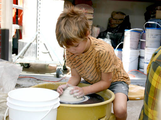 Eliott Carey, 5, shapes a mound of clay on a potters wheel on the patio of Peninsula Colleges ceramics studio Saturday at its second Fall Spectacular. Playing with clay was one of many activities for children, families and adults at the event, which included tours of classrooms and introductions to courses and fields of study, Port Angeles Farmers Market booths, live music and an exhibition of art by college faculty. The event was a way for the people to learn about Peninsula College, meet faculty and staff and connect with community resources. Fall quarter at the college starts Sept. 26. (Paula Hunt/Peninsula Daily News)