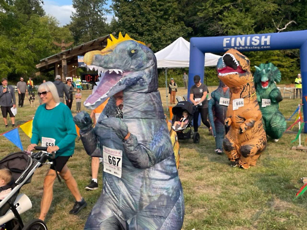 Geremy Jenkin of Bremerton leads his dinosaur pack of N. Jenkin, 11 (666) and Robin Jenkin, 16 (668) in the Quilcene Oyster Run 5K in Quilcene on Sunday. (David Goetz)