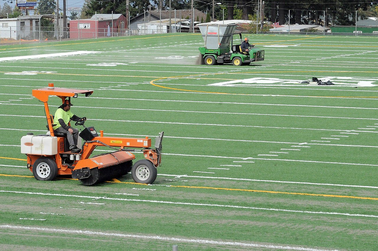 Tim Morland, front, and Rich Lear of Tualatin, Ore.-based Field Turf USA add fill to the playing surface at the new Monroe Athletic Field on Tuesday at the site of the former Monroe School near Roosevelt Elementary School in Port Angeles. The synthetic turf field, which is expected to be completed by mid-autumn, is being developed by the Port Angeles School District and will be available for community athletic events. (Keith Thorpe/Peninsula Daily News)