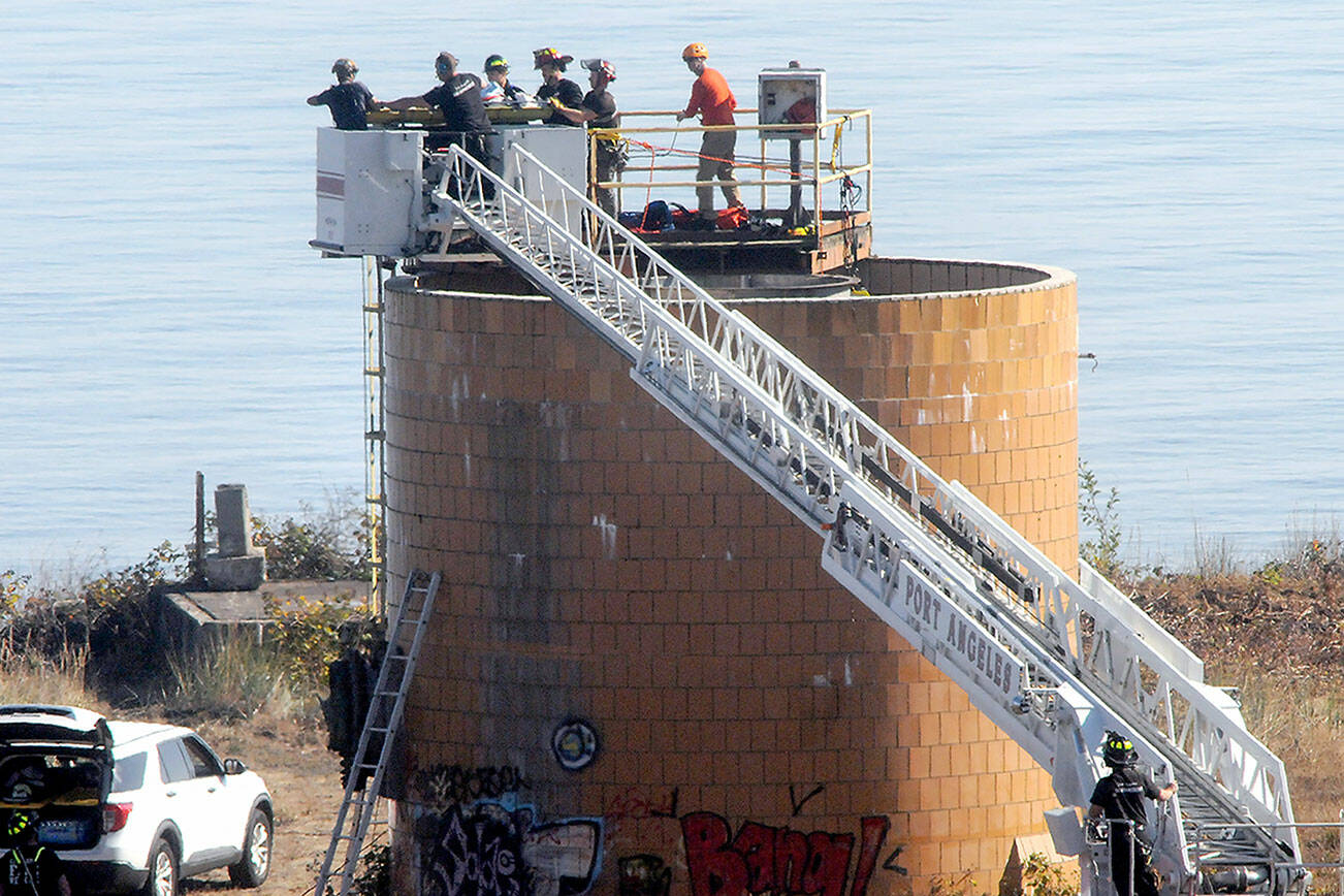 Port Angeles firefighters and a Clallam County technical rescue team place a litter onto a ladder track after pulling a person from a water tank at the site of the former Rayonier pulp mill on Thursday morning in Port Angeles. (Keith Thorpe/Peninsula Daily News)