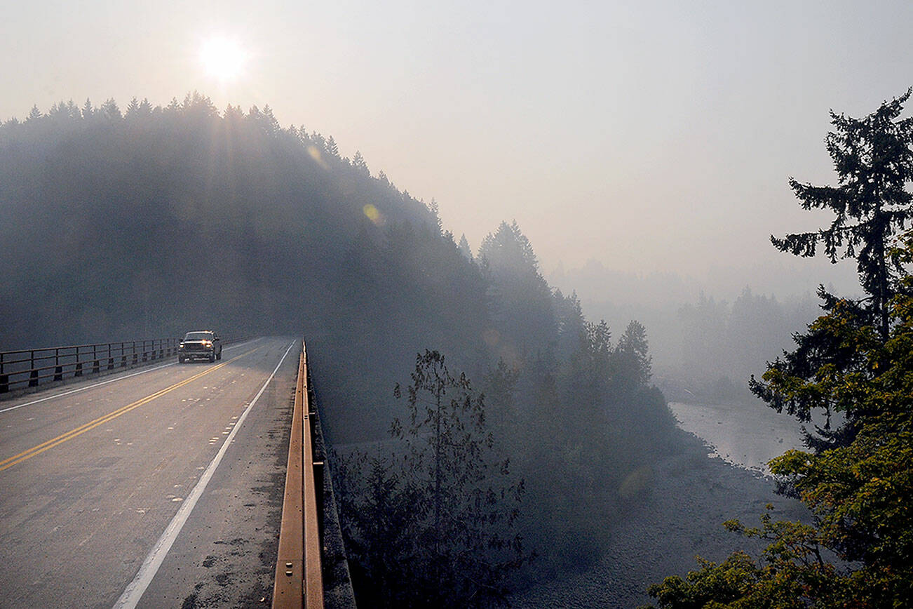 KEITH THORPE/PENINSULA DAILY NEWS
A vehicle makes its way across the Elwha River Bridge west of Port Angeles on Friday morning as a plume of wildfire smoke filters down the river valley. The smoke, which originated from seven named wildfires near the center of Olympic National Park, settled through the Elwha drainage to lower elevations, creating hazardous air in lower portions of the valley and unhealthy conditions in surrounding areas.