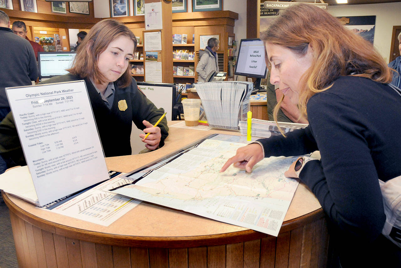 Olympic National Park visitor Sandra Schmidt of Leipzig, Germany, right, looks over a map of the park with interpretive ranger Emily Ryan on Friday at the park’s visitor center in Port Angeles. (KEITH THORPE/PENINSULA DAILY NEWS)