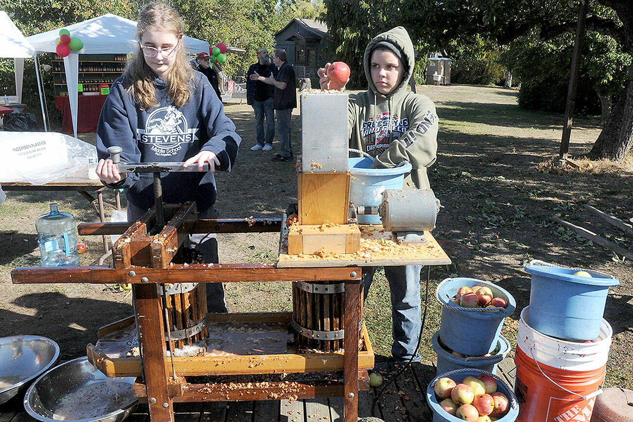 Michaela Christiansen, 14, left, and Pen DeBord, 14, both of Port Angeles, use a cider press to crush fresh apples into juice and pulp during Saturday’s Applestock celebration in Sequim. The event, a benefit for several area charities, featured food, music, crafts and games in the orchard at Williams Manor B&B/Vacation Rental. Applestock 2023 beneficiaries were the Salvation Army Food Bank, Angel Tree Christmas, Coats for Kids and area food banks. (Keith Thorpe/Peninsula Daily News)