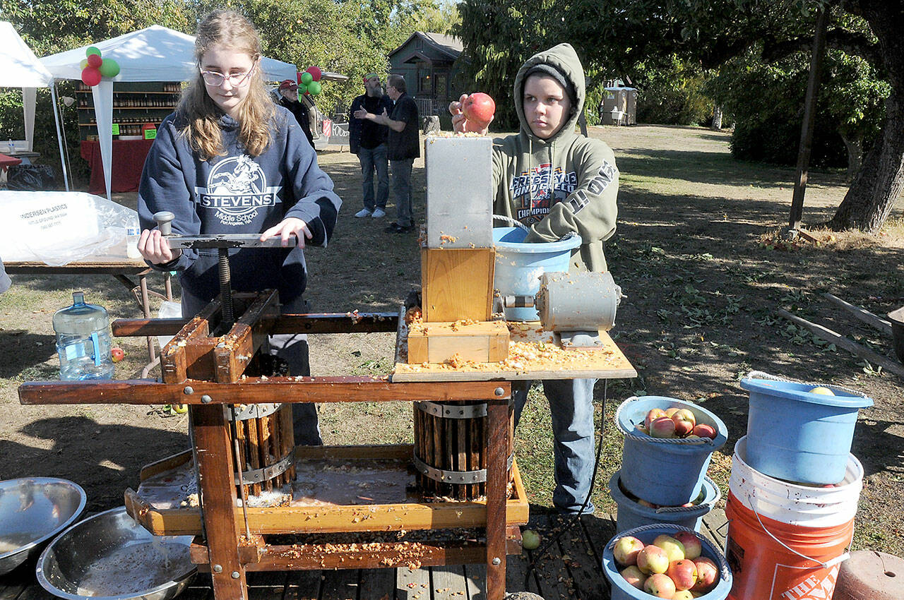 Michaela Christiansen, 14, left, and Pen DeBord, 14, both of Port Angeles, use a cider press to crush fresh apples into juice and pulp during Saturday’s Applestock celebration in Sequim. The event, a benefit for several area charities, featured food, music, crafts and games in the orchard at Williams Manor B&B/Vacation Rental. Applestock 2023 beneficiaries were the Salvation Army Food Bank, Angel Tree Christmas, Coats for Kids and area food banks. (Keith Thorpe/Peninsula Daily News)