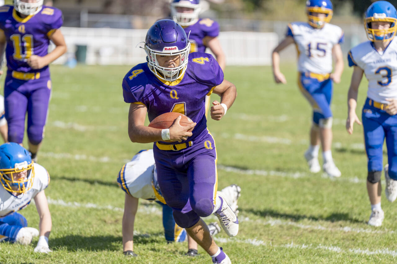 Quilcene’s Andrew Perez runs for yardage against Crescent on Saturday in Quilcene. In on the play are Crescent’s Conner Bauers (3) and Henry Bourm (15). (Steve Mullensky/for Peninsula Daily News)
