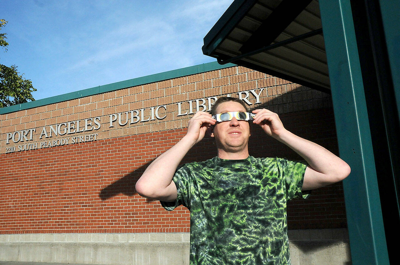 Jeff Clark, facilities technician for the North Olympic Library System, wears special glasses to observe Saturday’s partial eclipse of the sun in front of the Port Angeles Public Library. The annular eclipse was visible as a “ring of fire” for a swath of watchers across Oregon to Texas and Mexico, was visible on the North Olympic Peninsula at about 80 percent with a large portion of the solar disc obscured by the Moon. (Keith Thorpe/Peninsula Daily News)