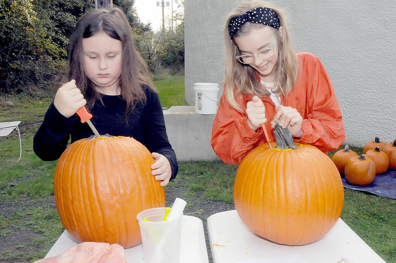 Armed with matching knives, Emma Briggance, 10, left, and Layla Newlon, 12, both of Port Angeles, prepare pumpkins for decorating during a pumpkin carving workshop on Saturday at the Port Angeles Fine Arts Center. Jack-o’-lanterns created during the session were to be displayed in a pumpkin walk in the nearby Webster’s Woods Sculpture Park. (Keith Thorpe/Peninsula Daily News)