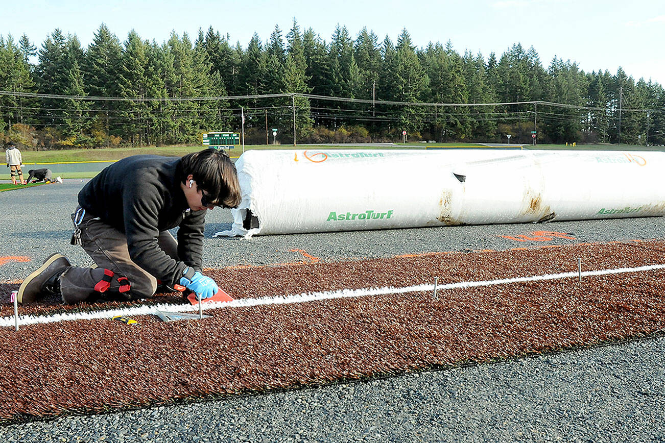 KEITH THORPE/PENINSULA DAILY NEWS
Joey Butcher of Seattle-based Coast to Coast Turf installs a foul line at the baseball diamond at Volunteer Field in Port Angeles on Thursday as part an upgrade to the sports facility. The infield area of the diamond is being replaced with an artificial surface, cutting down on continual maintenance to the diamond.